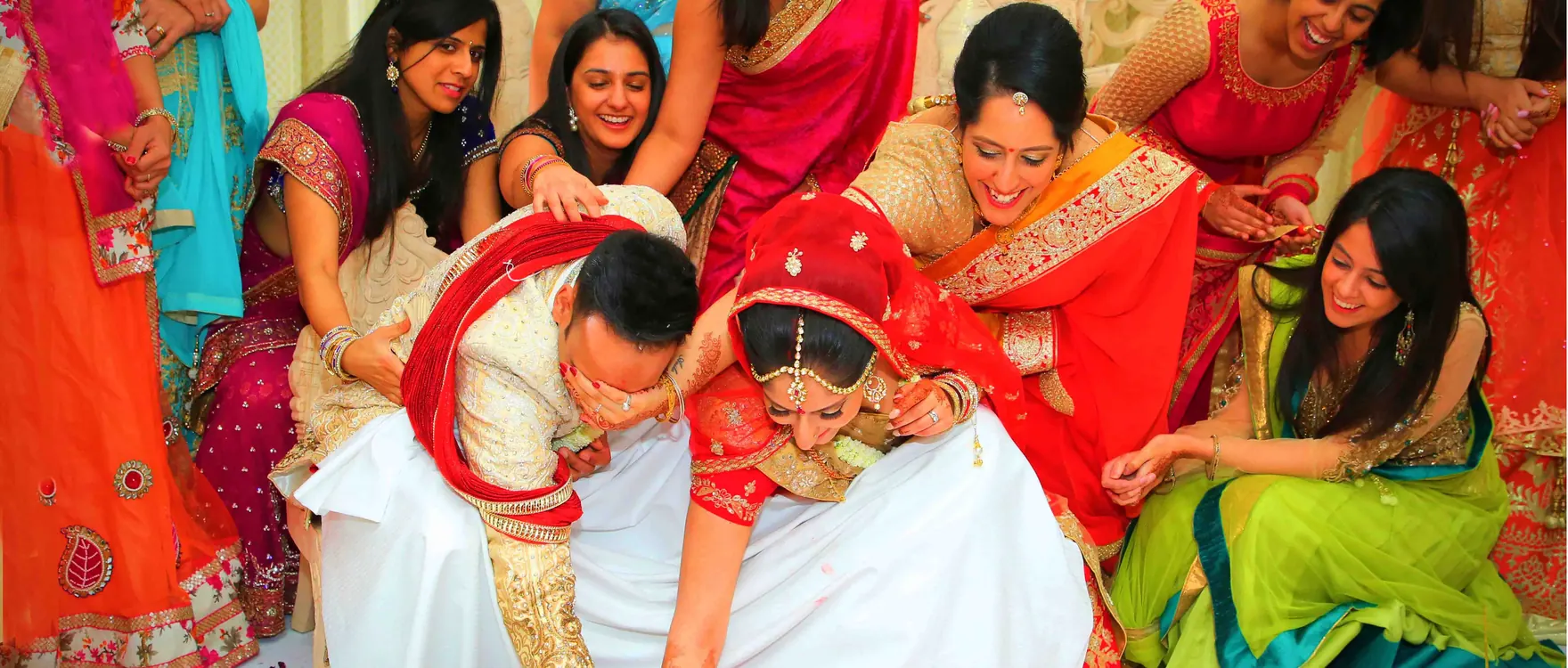 Bride in red surrounded by women in bright saris at a wedding celebration